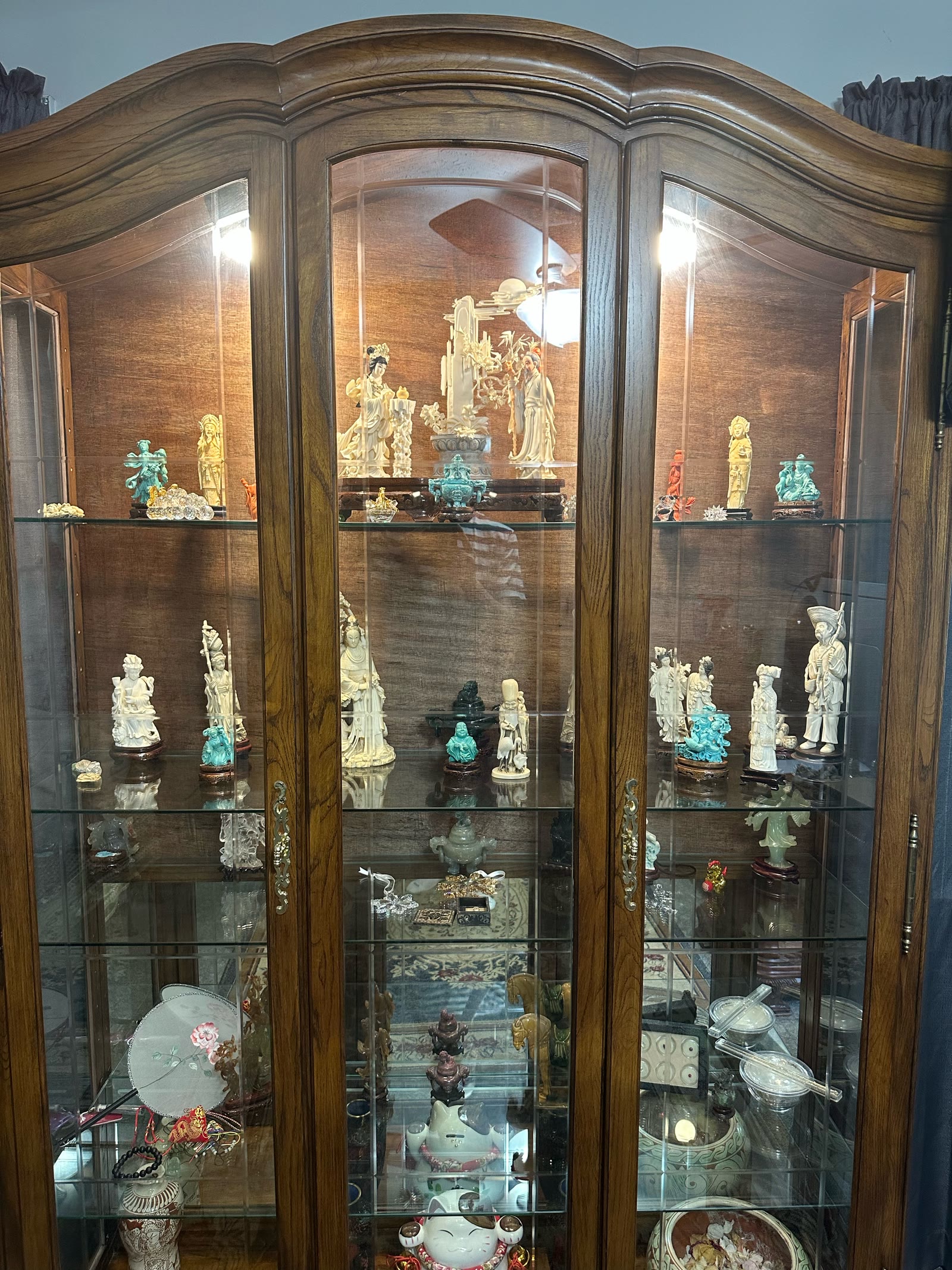 A wood china cabinet filled with figurines.