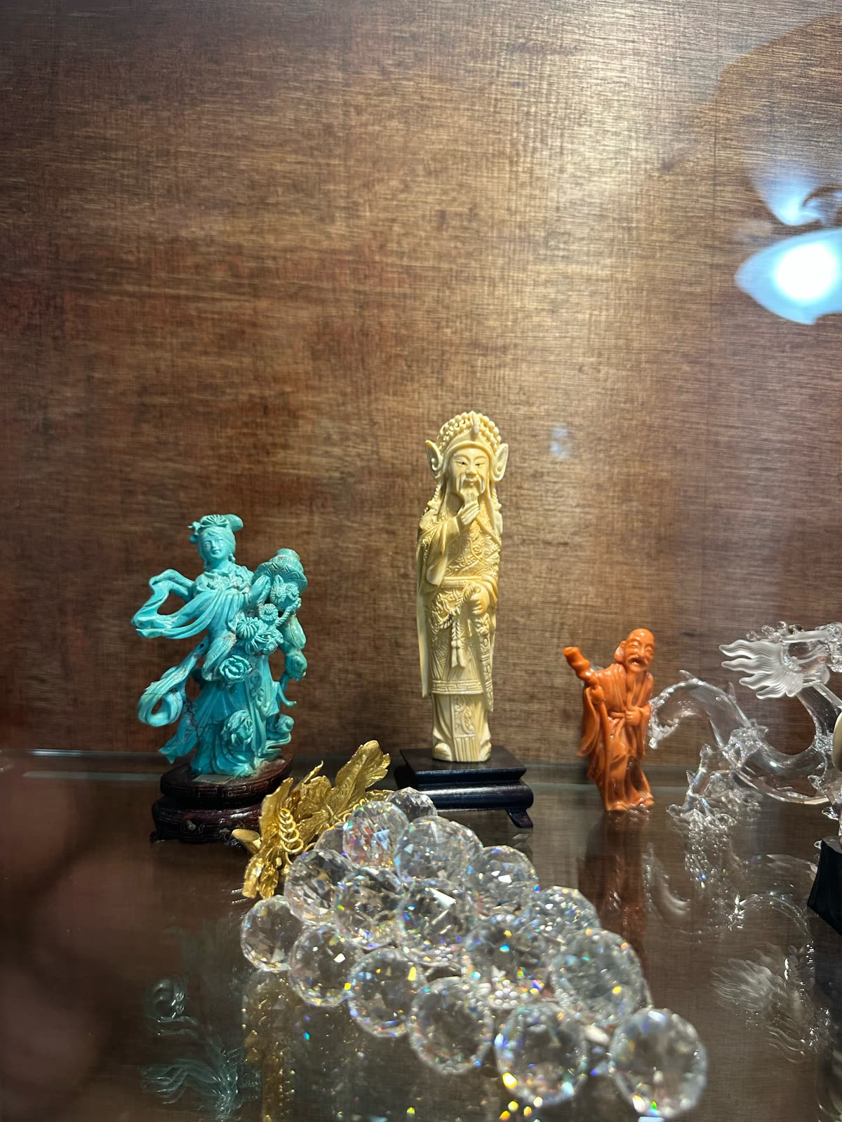 Figurines standing on a glass shelf.